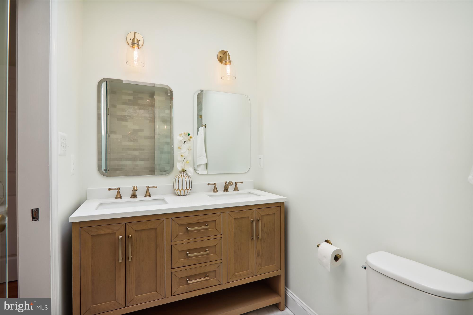 2462 Tunlaw Road Northwest Washington, DC 20007 - Photo 27 of 56 a bathroom with a double vanity sink toilet and mirror