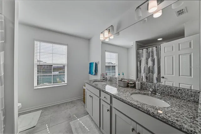 a bathroom with a granite countertop sink a mirror and a shower