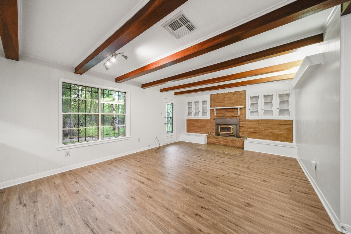2019 North Thompson Street, Unit A Conroe, TX 77301 - Photo 2 of 17 Wood beam living room with built in storage surrounding wood burning fireplace.