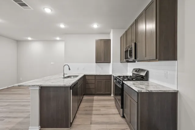 a kitchen with stainless steel appliances granite countertop a sink stove and refrigerator