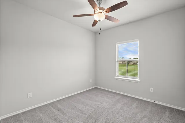 an empty room with a window and a fan
