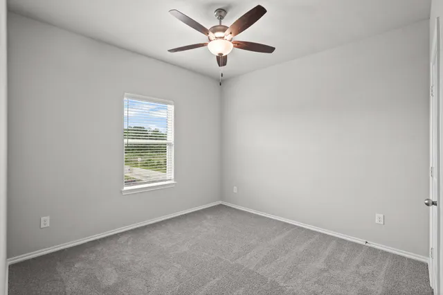 an empty room with a window and a fan