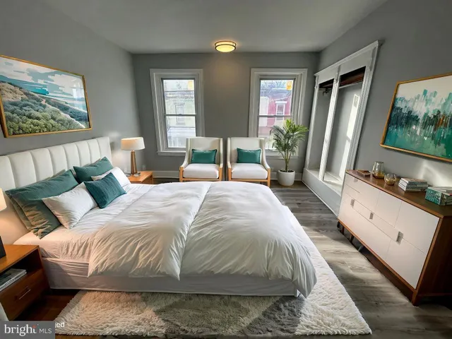 a spacious bedroom with a bed a mirror on dresser and a large window