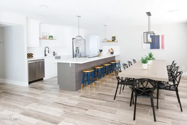 a view of kitchen with stainless steel appliances kitchen island a table chairs in it and wooden floors