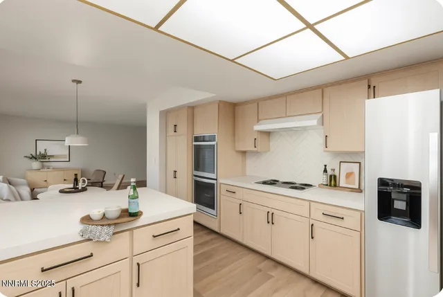 a kitchen with stainless steel appliances granite countertop a sink a stove a refrigerator and white cabinets