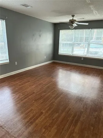 an empty room with wooden floor and windows