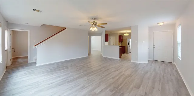 an empty room with wooden floor and ceiling fan
