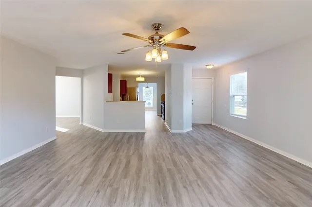 a view of an empty room with window and wooden floor