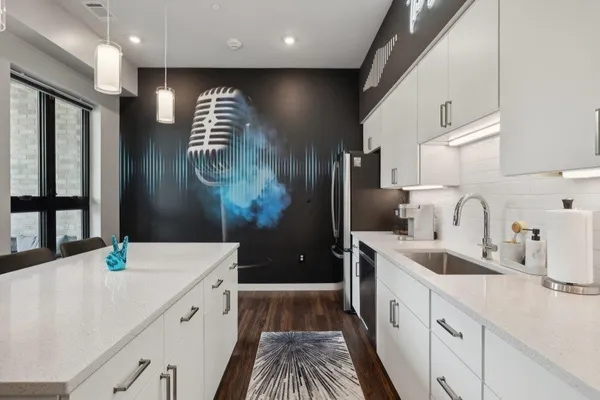 a kitchen with stainless steel appliances a refrigerator a sink a stove and white cabinets
