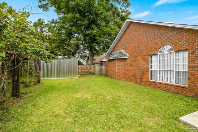 a backyard of a house with lots of green space and tree in the background