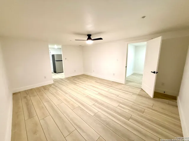 an empty room with wooden floor and ceiling fan