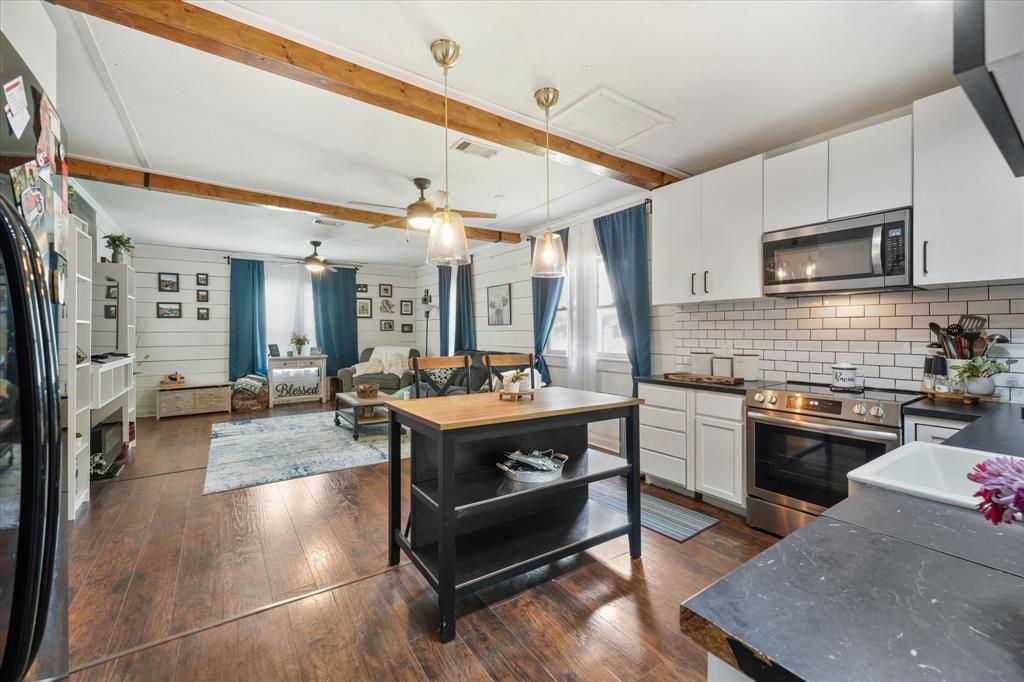 a large kitchen with stainless steel appliances granite countertop a stove and a view of living room