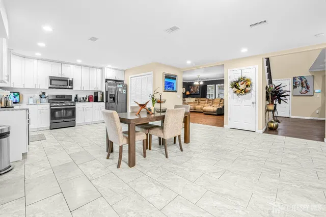 a living room with stainless steel appliances furniture and a kitchen view