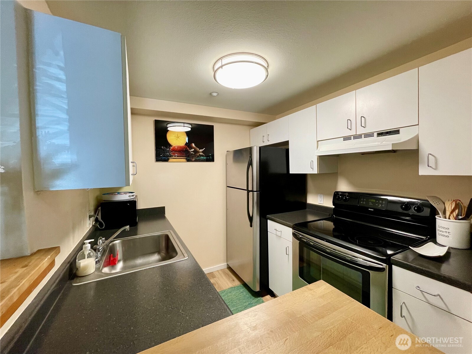 1415 2nd Avenue, Unit 1106 Seattle, WA 98101 - Photo 14 of 30 a kitchen with a refrigerator a stove a sink and a stove with wooden floor