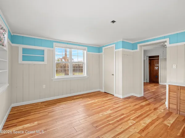 a view of empty room with wooden floor and fan