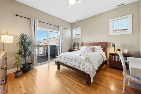 a bed sitting in a spacious bedroom next to a window and potted plants