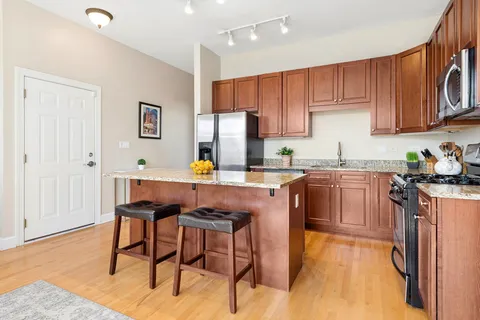 a kitchen with stainless steel appliances granite countertop a stove a sink dishwasher and a refrigerator with wooden cabinets
