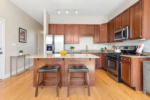 a kitchen with stainless steel appliances granite countertop a stove top oven a sink dishwasher and cabinets with wooden floor