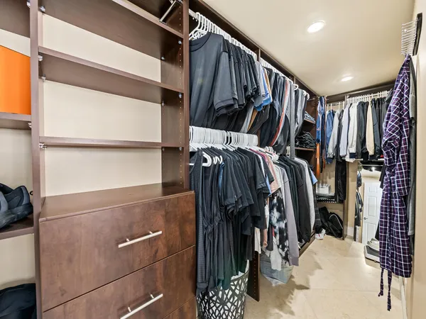 a view of walk in closet with clothes and shoes