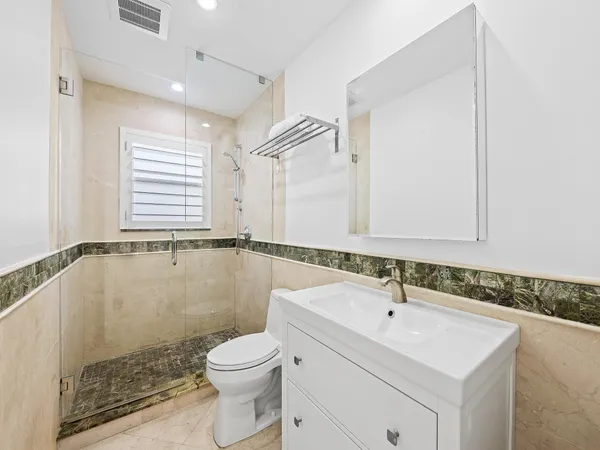 a bathroom with a sink a toilet a mirror and shower