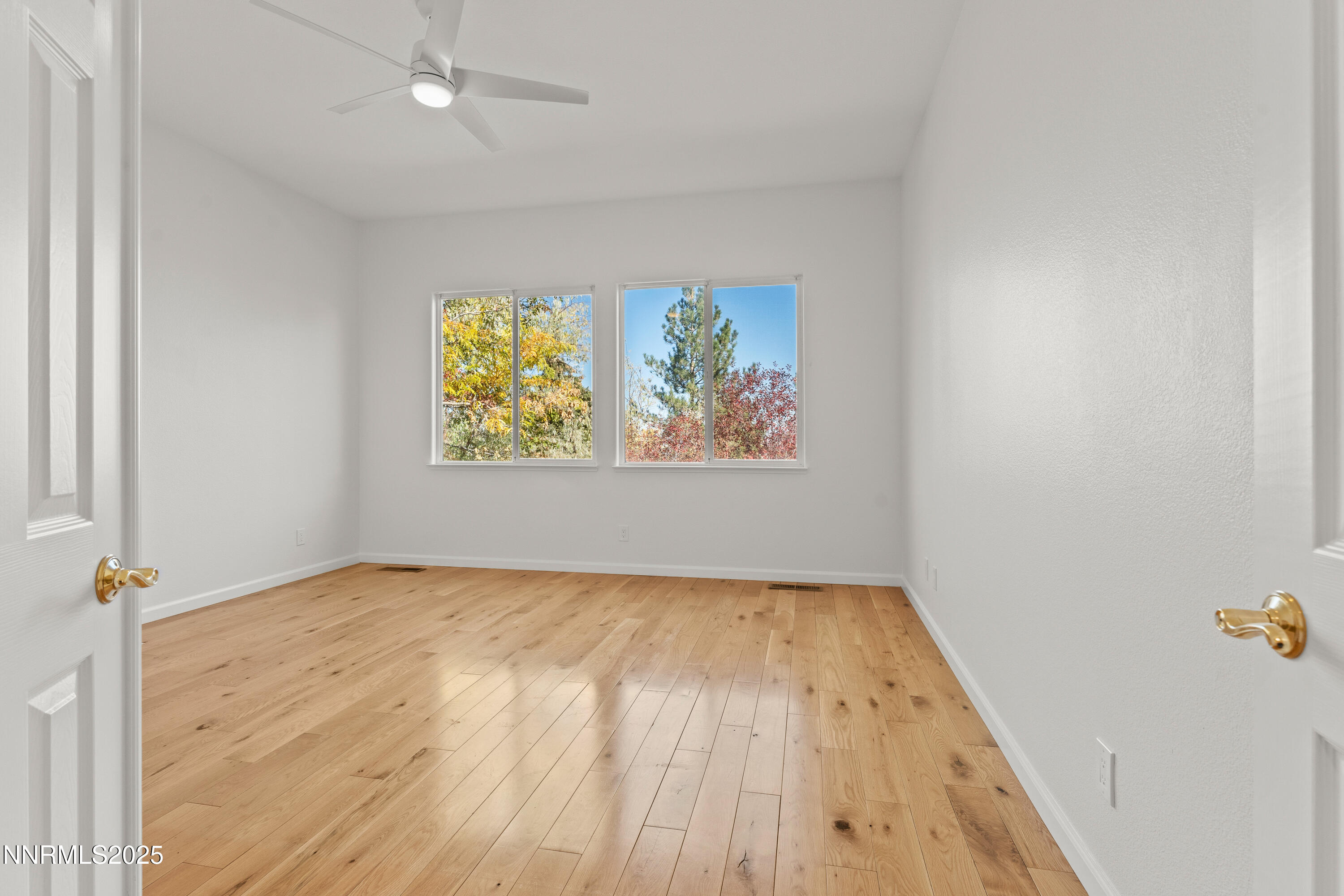 4991 West Albuquerque Road Reno, NV 89511 - Photo 23 of 60 an empty room with wooden floor ceiling fan and windows