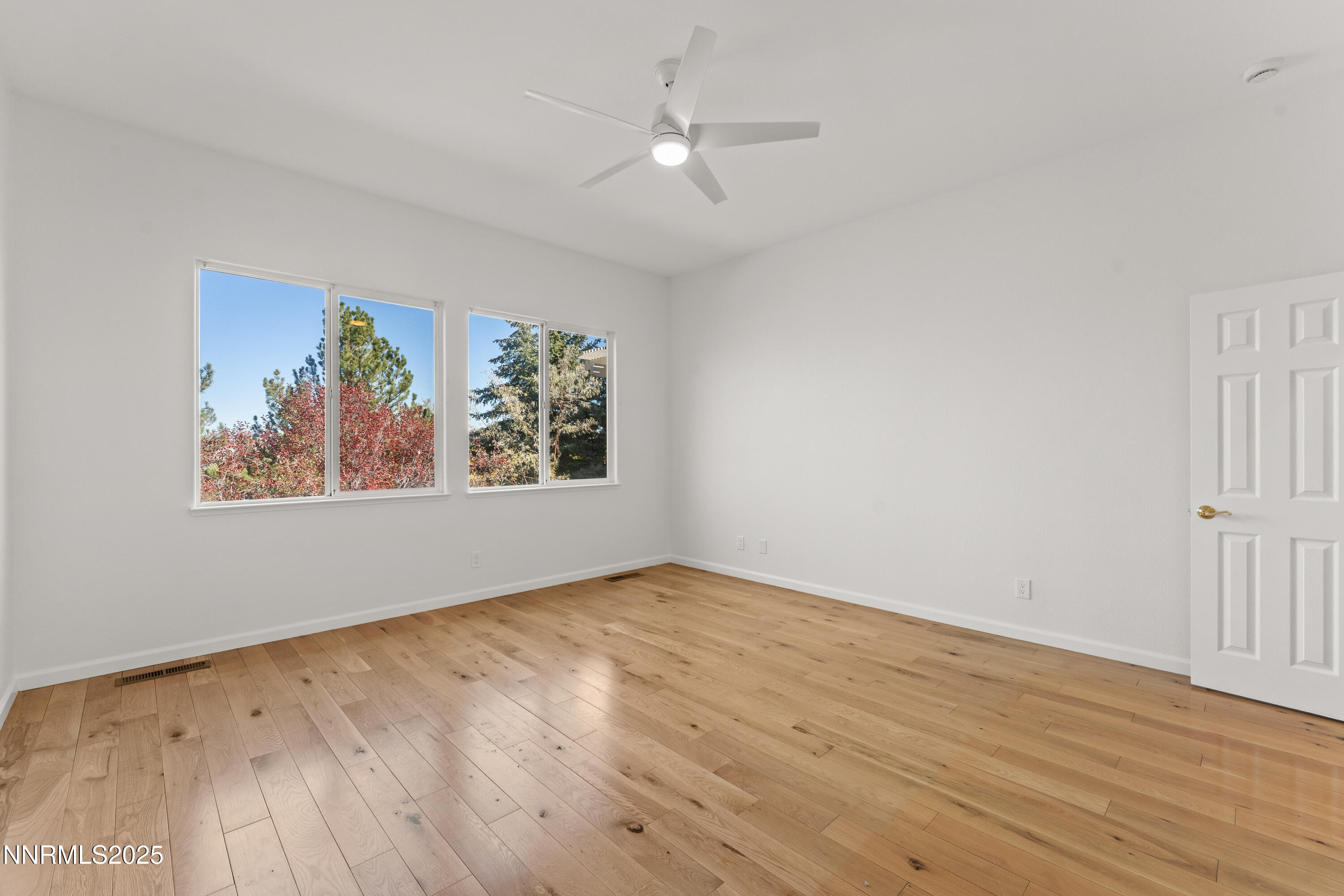 4991 West Albuquerque Road Reno, NV 89511 - Photo 25 of 60 an empty room with wooden floor ceiling fan and windows