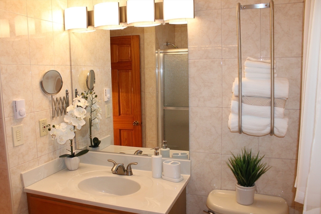 28 State Street Chicopee, MA 01013 - Photo 22 of 25 a bathroom with a sink a mirror a potted plant and a shower