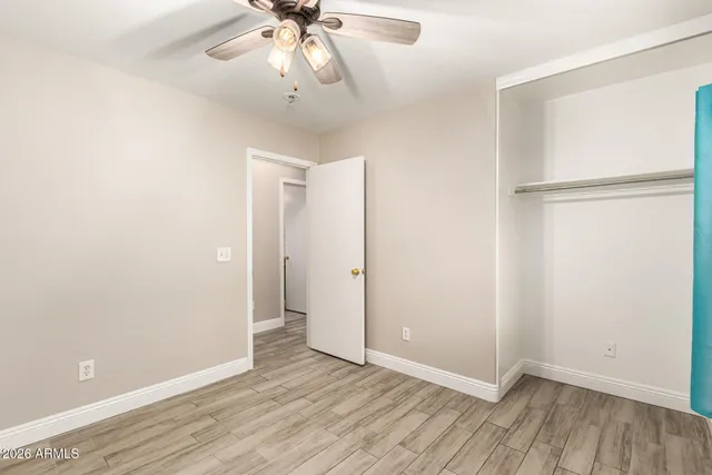 an empty room with wooden floor and fan