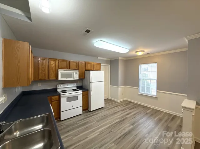 a kitchen with granite countertop a stove a sink and a refrigerator