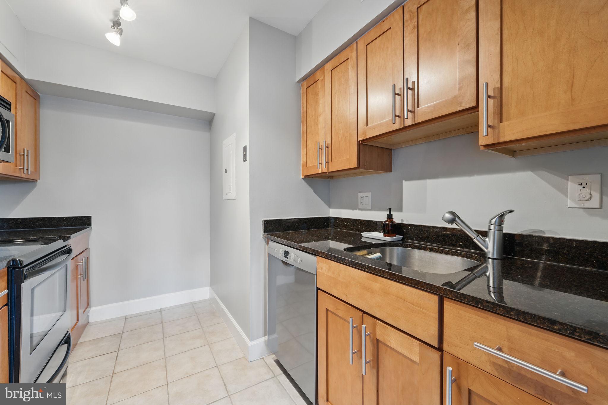 3611 38th Street Northwest, Unit 209 Washington, DC 20016 - Photo 7 of 30 a kitchen with granite countertop a sink stainless steel appliances white cabinets and a window