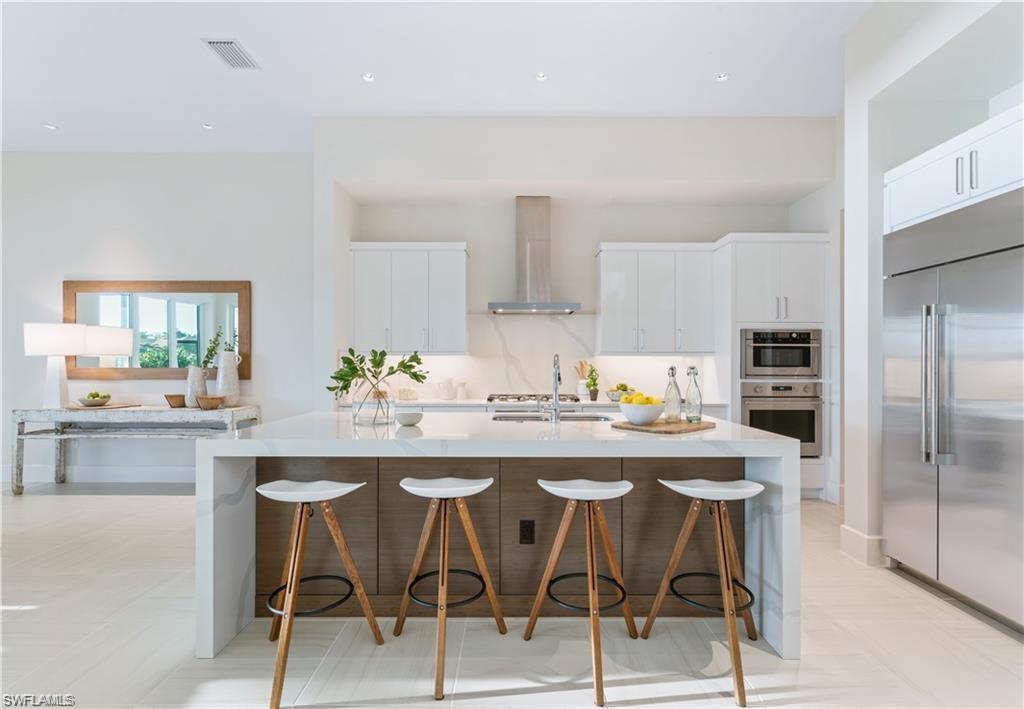 16745 Cabreo Drive Naples, FL 34110 - Photo 3 of 29 a kitchen with stainless steel appliances kitchen island granite countertop a dining table chairs and a refrigerator