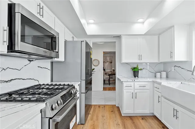 a kitchen with stainless steel appliances white cabinets a stove top oven