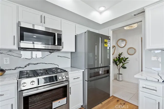 a kitchen with stainless steel appliances white cabinets a refrigerator and a stove