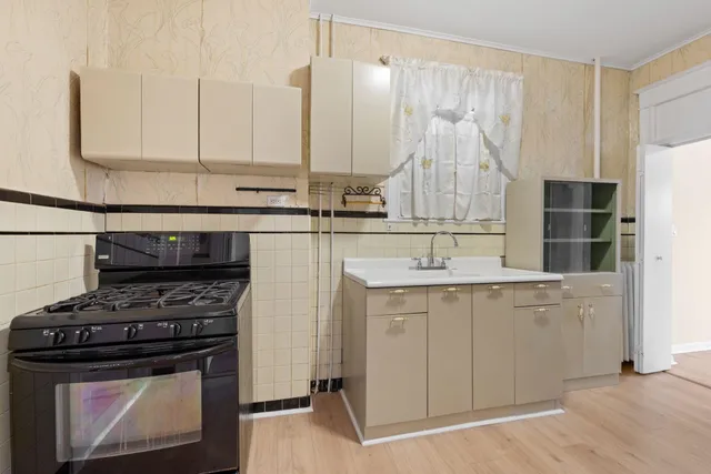a kitchen with stainless steel appliances a stove a sink and white cabinets