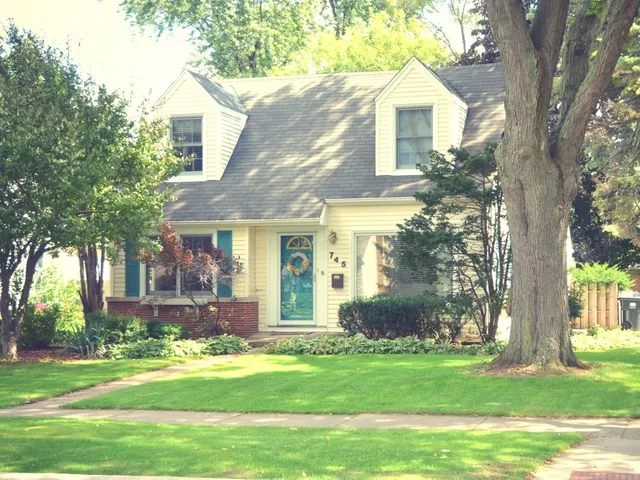a front view of a house with a yard and trees