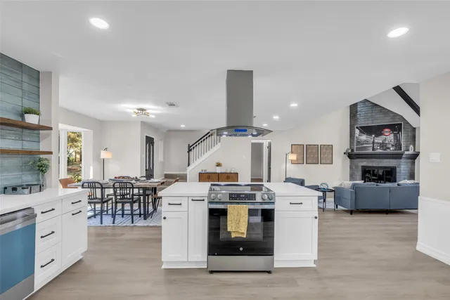 a large white kitchen with stainless steel appliances kitchen island granite countertop a stove and a sink