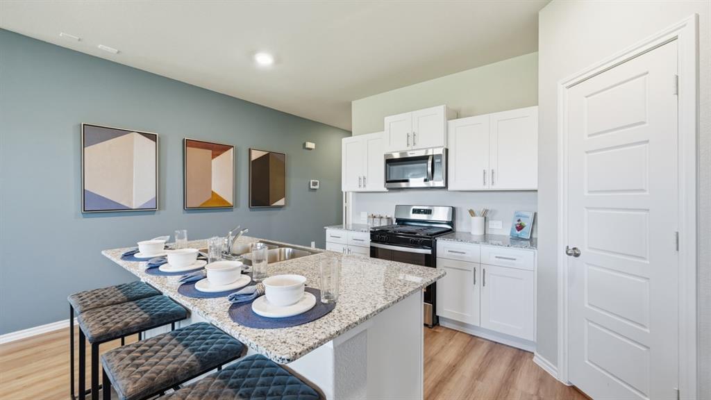16536 Hudson Pr Way Justin, TX 76247 - Photo 2 of 39 a kitchen with stainless steel appliances kitchen island granite countertop a sink a stove a table and chairs