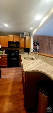 a kitchen with kitchen island granite countertop a refrigerator a stove and a wooden cabinets