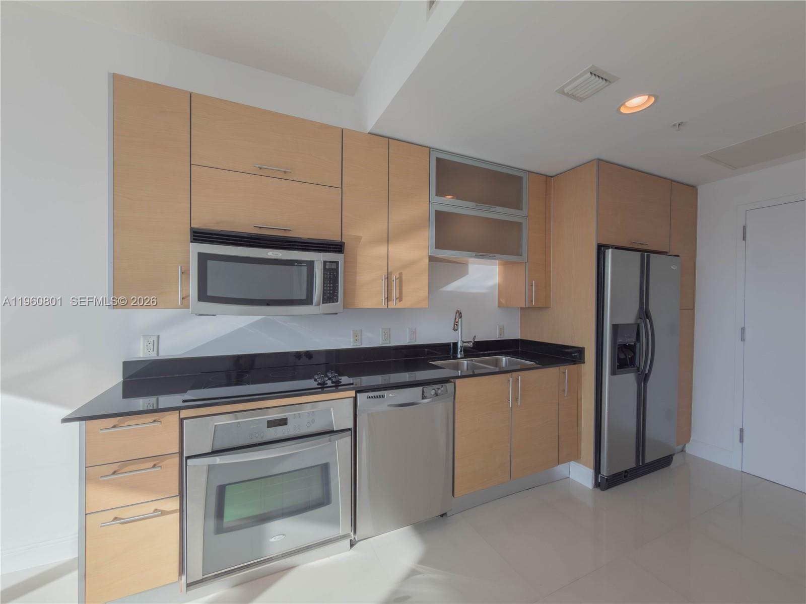60 Southwest 13th Street, Unit 1605 Miami, FL 33130 - Photo 2 of 30 a kitchen with granite countertop a stove and a refrigerator