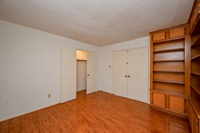 a view of empty room with wooden floor and closet