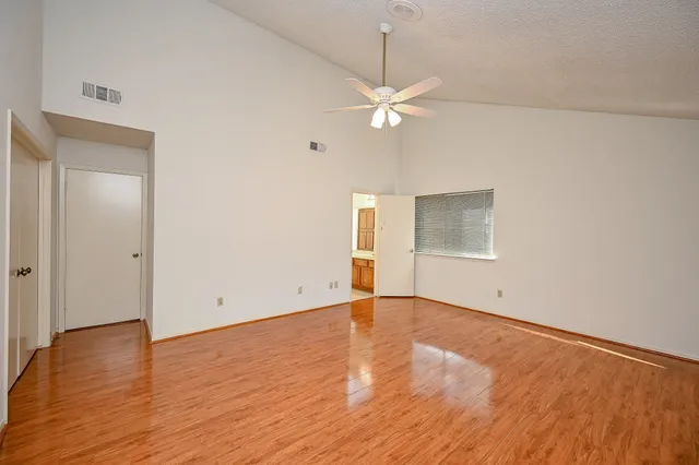 an empty room with wooden floor and ceiling fan