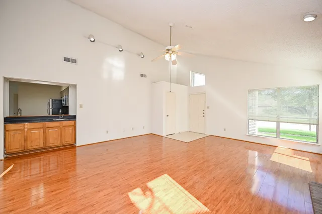 a view of empty room with wooden floor and fan