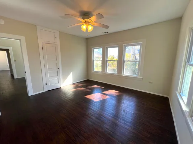 an empty room with wooden floor and windows
