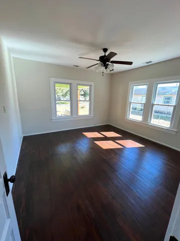 a view of an empty room with window and wooden floor