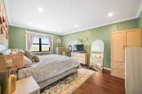 a bedroom with a bed wooden floor and window