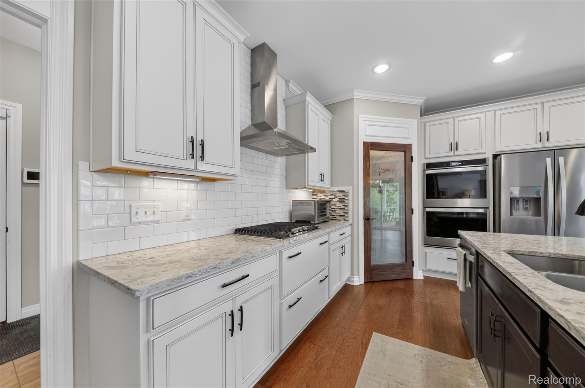 2531 Walnut View Drive Howell, MI 48855 - Photo 13 of 34 Kitchen featuring white shaker cabinetry, stainless steel appliances, a subway tile backsplash, and wood-finish flooring