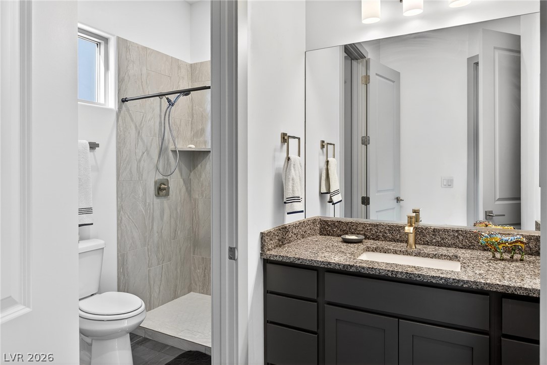 1460 Blue Ridge Trail Mesquite, NV 89027 - Photo 15 of 39 A well-appointed bath features a tiled shower and a vanity with stone counters, illuminated by soft overhead lighting.