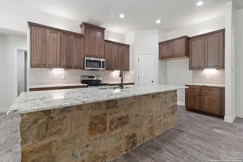 a kitchen with granite countertop a stove top oven sink and cabinets