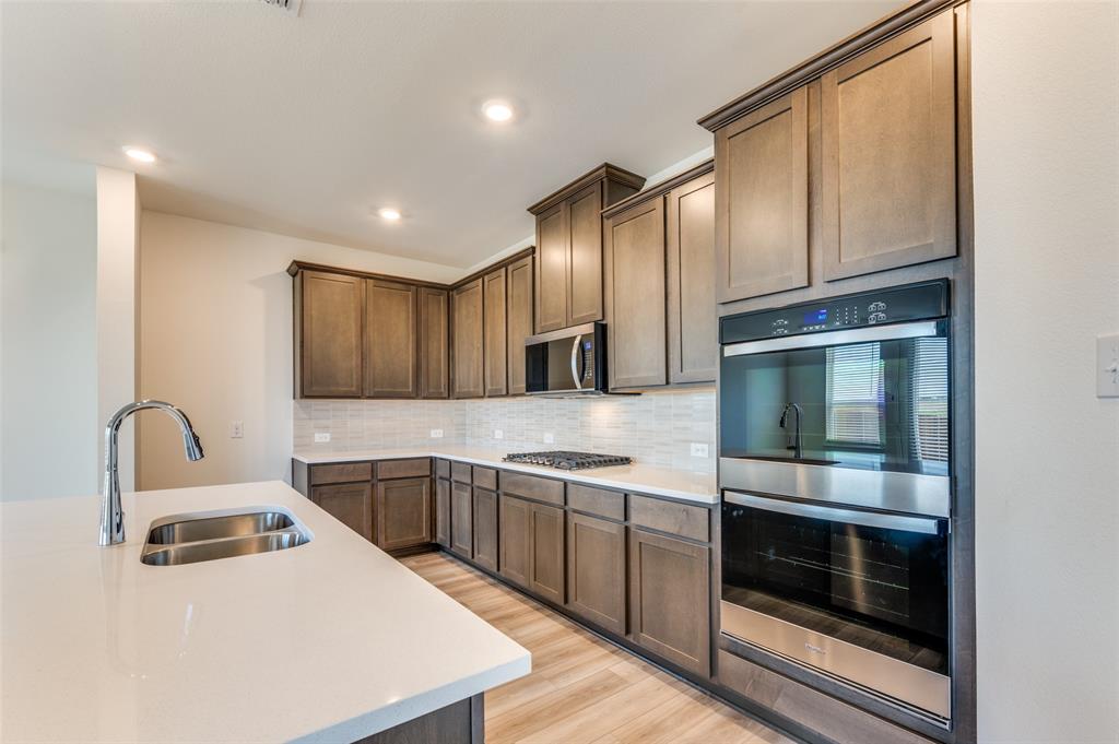 341 Fallbrook Drive Aledo, TX 76008 - Photo 10 of 40 Kitchen featuring stainless steel appliances, light countertops, decorative backsplash, light wood-style flooring, and recessed lighting