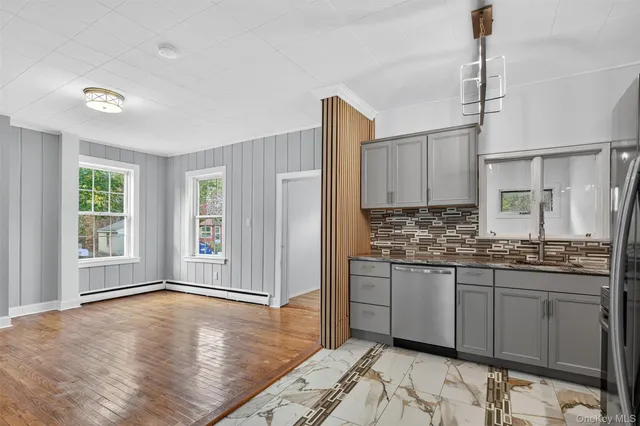 a kitchen with stainless steel appliances granite countertop a stove a sink and white cabinets with wooden floor